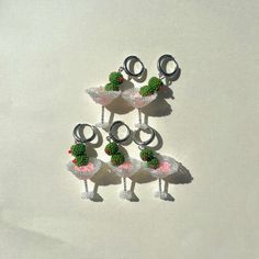 four small ornaments are arranged in the shape of sheeps with flowers on their heads