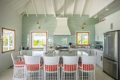 a kitchen with white and red chairs around a table in front of a stove top oven