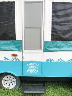 a blue and white camper parked in the grass