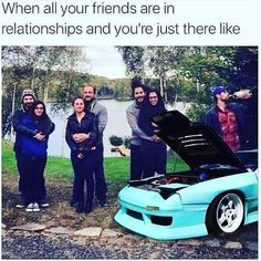 a group of people standing next to a blue sports car