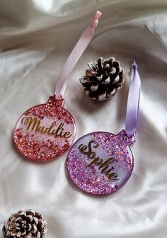 three personalized christmas ornament ornaments on a white sheet with pine cones in the background