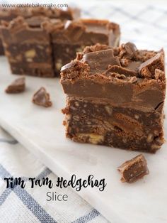 three pieces of chocolate fudge cake sitting on top of a white plate with the words tim tam hegelberg slice above it