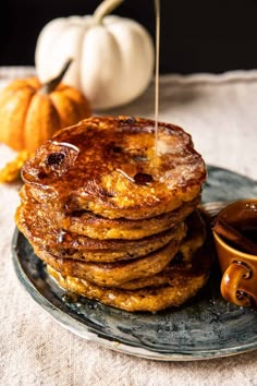 stack of pancakes with syrup being drizzled over them on a blue plate