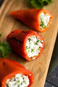 three stuffed tomatoes on a cutting board with parsley