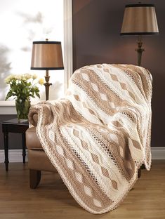 a living room with a chair, lamp and a blanket on the floor in front of a window