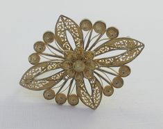 A beautiful gold over sterling silver filigree brooch depicting a flower set in a geometric pattern. Intricate design and very detailed. Some patina on it. C clasp. Please ask for additional pictures. Not marked, but tested as sterling silver. Some markings on the clasp and pin, but I can't identify them. Measurements: approx. 1.7 inches long and approx. 1.3 inches wide Please note that due to lighting effects, monitor's brightness, contrast and other settings, there might be some slight differe Gold Filigree Ornate Brooches, Ornate Gold Filigree Brooches, Gold Filigree Brooches As Gifts, Gold Filigree Brooches For Wedding, Elegant Gold Filigree Brooches, Yellow Gold Filigree Brooches For Wedding, Gold Filigree Wedding Brooches, Wedding Yellow Gold Filigree Brooches, Ornate Brooches With Intricate Design As Gift