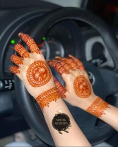 a woman's hands with hennap on her hand in a car steering wheel