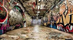 an empty hallway with graffiti all over the walls