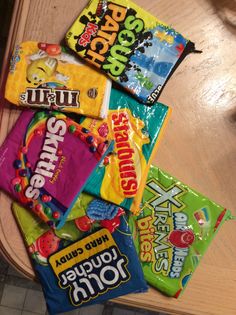 a pile of candy sitting on top of a wooden table next to a bag of chips