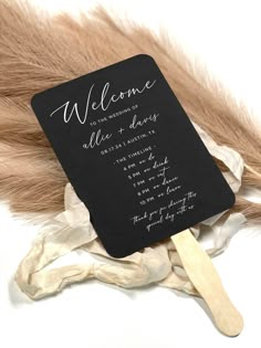 a black and white welcome card on top of some feathers