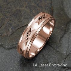 a rose gold wedding ring with an intricate design on the outside and inside, sitting on top of a rock