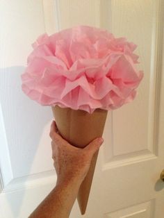 a hand holding a paper cone with pink ruffles on it's top