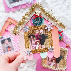 a person holding up a small house with pictures on the front and side of it