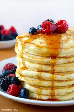 a stack of pancakes with syrup and berries on the side