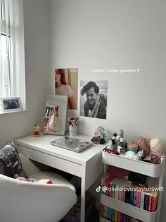 a white desk and chair in front of a window with pictures on the wall above it