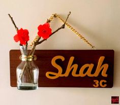 a wooden sign hanging on the wall with flowers in a glass vase next to it