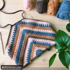 a crocheted purse sitting on top of a wooden table next to some yarn