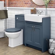 a white toilet sitting next to a blue sink in a bathroom under a brick wall