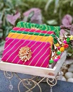 three different colored bags sitting on top of a metal cart next to flowers and rocks