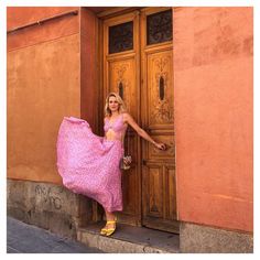 a woman in a pink dress leaning against a door