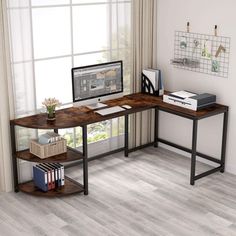 a computer desk sitting in front of a window next to a book shelf with books on it