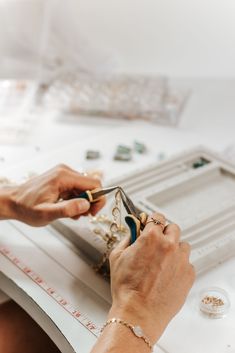 a woman is working on jewelry with scissors