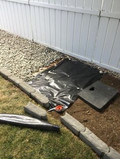 some concrete blocks laying on the ground in front of a fence and a building with white siding