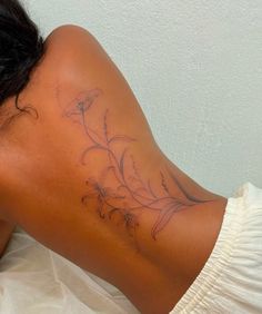 a woman laying on top of a bed with her back turned to the camera and tattoos on her upper half