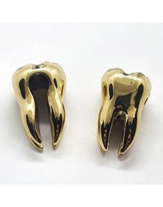 two gold colored metal objects on a white surface, one is shaped like an animal's mouth