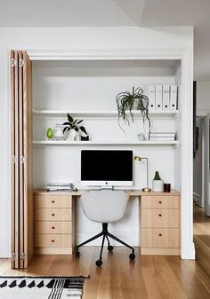 a desk with a computer on top of it in front of a bookshelf