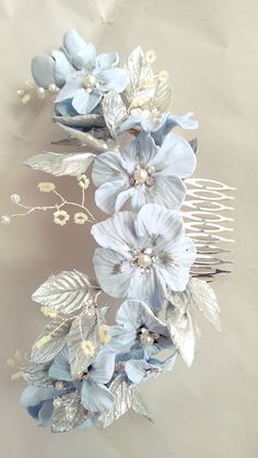 a hair comb with blue flowers and leaves on it's headpiece, sitting on a table