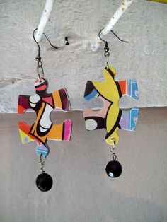 two pairs of colorful earrings hanging from hooks on a white surface with snow in the background