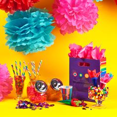 colorful paper flowers and candy are hanging from a yellow background with confetti on the floor