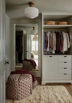 a closet with clothes hanging on the wall and a footstool in front of it