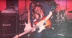 a person with long hair playing an electric guitar in front of a microphone and amp