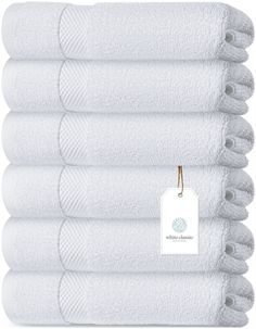 six white towels stacked on top of each other with a tag hanging from the front