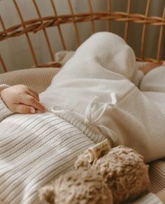 a baby laying in a crib next to a teddy bear