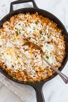 a skillet filled with cheese and meat covered in gravy on top of a white cloth