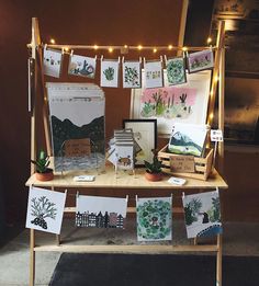 a table topped with pictures and cards on top of a wooden table covered in string lights