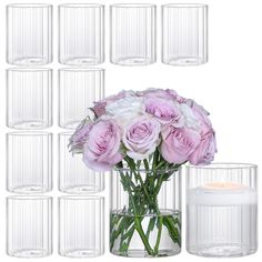 a vase filled with lots of pink flowers next to a white candle and some glasses