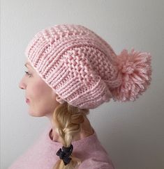 a woman wearing a pink knitted hat with pom - poms