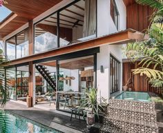 a house that is next to a pool with plants in the yard and stairs leading up to it