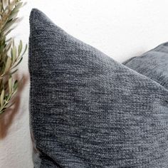 a close up of a gray pillow on a white wall