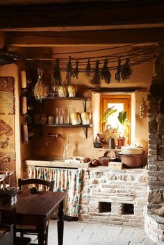 an old fashioned kitchen with pots and pans hanging from the ceiling, next to a brick oven