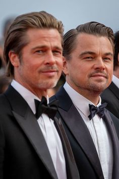 two men in tuxedos standing next to each other on the red carpet at an event