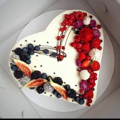 a heart shaped cake decorated with berries, raspberries and strawberries