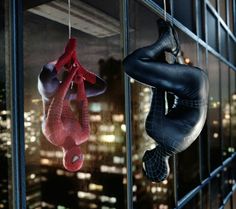 two spider - man hanging from the side of a building in front of a city at night