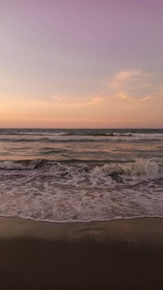 the ocean waves are coming in to shore at sunset with purple and blue skies above