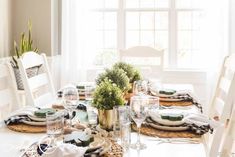 a dining table with place settings and plates on it, in front of a window