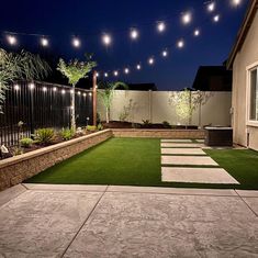 a backyard with grass and lights strung over it